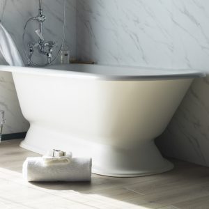 Elegant white freestanding bathtub with chrome fixtures, set against a marble wall in a luxurious bathroom, perfect for relaxation and styled with premium bathroom fixtures from Albion Bath Co Ltd.